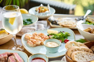 Masada bir sürü farklı lezzetli yemek var. Masada çeşitli abur cuburlar ve antipastalar var. Süslü deniz ürünleri tabağı. Tabakların çeşitleri masada. Restoran menüsü.