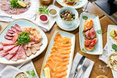 Restoranda et tartarı var. Tabakların çeşitleri masada. Masada çeşitli abur cuburlar ve antipastalar var. Restoran menüsü. İtalyan mutfağı