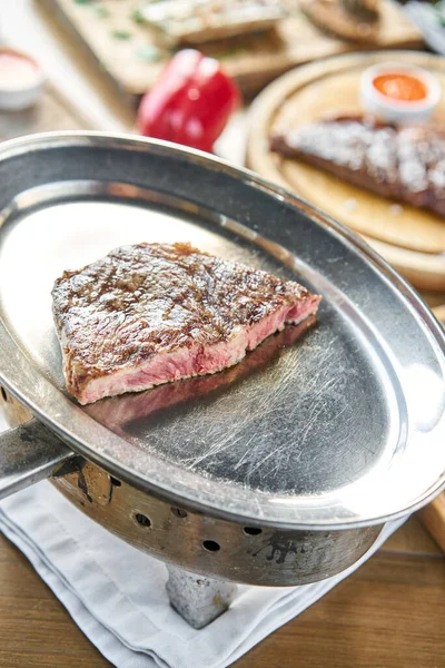 Izgara çizgili biftek. Ya biftek ya da kömürlü metal bir tabakta New York şeridi. Barbekü restoran menüsü.