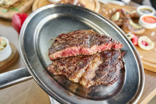 Grilled striploin steak. The strip steak or New York strip On a metal plate with coal. Barbecue restaurant menu.