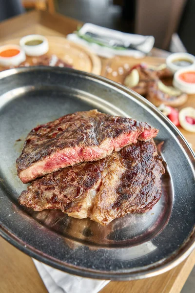 Grilled striploin steak. The strip steak or New York strip On a metal plate with coal. Barbecue restaurant menu.
