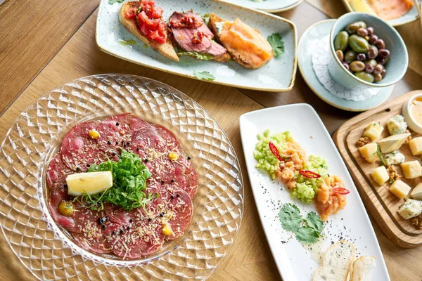 Carpaccio de ternera con caviar balsámico y queso parmesano. Varios aperitivos y antipasti en la mesa. Cocina italiana Menú de restaurante, concepto de comida natural y ecológica . — Foto de Stock