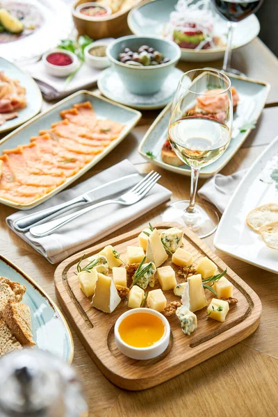 Cheese plate. Focus on delicious cheese mix with walnuts, honey on wooden table. Various snacks and antipasti on the table. Restaurant menu. — Stock Photo, Image