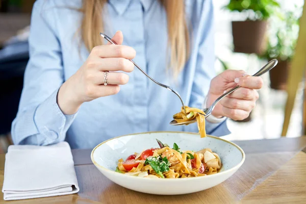 Frau isst italienische Pasta mit Meeresfrüchten und Tomatensauce. Pasta Gamberini. Tagliatelle in Großaufnahme wickeln sie mit einem Löffel um eine Gabel. Parmesankäse — Stockfoto