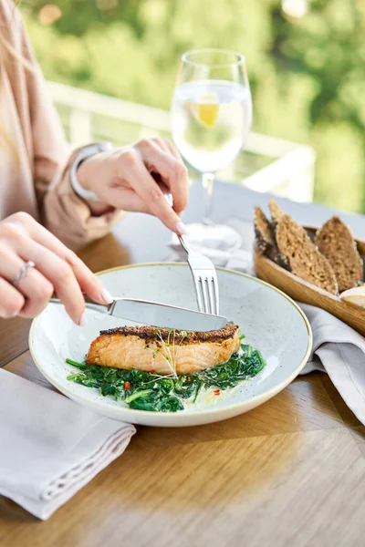 Salmon steak fillet with grainy mustard and spinach. Lunch in a restaurant, a woman eats delicious and healthy food. Restaurant menu, a series of photos of different dishes — Stock Photo, Image