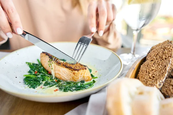 Salmon steak fillet with grainy mustard and spinach. Lunch in a restaurant, a woman eats delicious and healthy food. Restaurant menu, a series of photos of different dishes — Stock Photo, Image