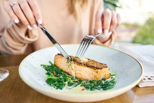 Salmon steak fillet with grainy mustard and spinach. Lunch in a restaurant, a woman eats delicious and healthy food. Restaurant menu, a series of photos of different dishes — Stock Photo, Image