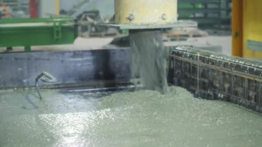 Büyük bir uzaktan kumandalı makine betonu form olarak doldurur. House-Building fabrikasının atölyesinde çalışanlar. Endüstriyel iç mekan. Beton fabrikası.