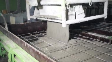 Büyük bir uzaktan kumandalı makine betonu form olarak doldurur. House-Building fabrikasının atölyesinde çalışanlar. Endüstriyel iç mekan. Beton fabrikası.