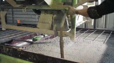 Büyük bir uzaktan kumandalı makine betonu form olarak doldurur. House-Building fabrikasının atölyesinde çalışanlar. Endüstriyel iç mekan. Beton fabrikası.