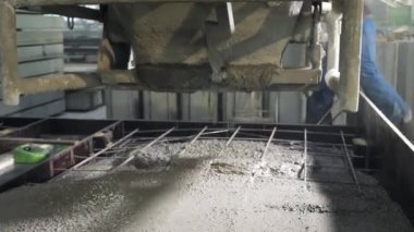 Büyük bir uzaktan kumandalı makine betonu form olarak doldurur. House-Building fabrikasının atölyesinde çalışanlar. Endüstriyel iç mekan. Beton fabrikası.