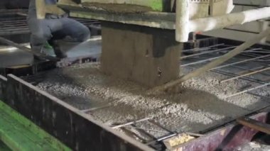 Büyük bir uzaktan kumandalı makine betonu form olarak doldurur. House-Building fabrikasının atölyesinde çalışanlar. Endüstriyel iç mekan. Beton fabrikası.