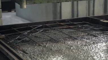 Büyük bir uzaktan kumandalı makine betonu form olarak doldurur. House-Building fabrikasının atölyesinde çalışanlar. Endüstriyel iç mekan. Beton fabrikası.