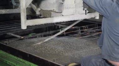 Büyük bir uzaktan kumandalı makine betonu form olarak doldurur. House-Building fabrikasının atölyesinde çalışanlar. Endüstriyel iç mekan. Beton fabrikası.