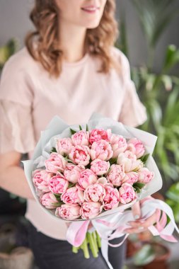 Kadın elinde pembe renkli laleler. Bahar buketi tutan genç ve güzel bir kadın. Bir demet taze bahar çiçeği dişilerin ellerinde