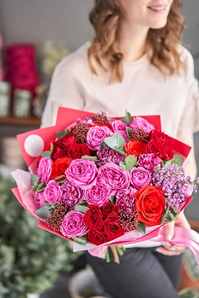 Fényes bogyó szín, gyönyörű csokor vegyes virágok a nők kezében. a virágárus munkája egy virágüzletben. Friss vágott virág. Európai virágüzlet. — Stock Fotó