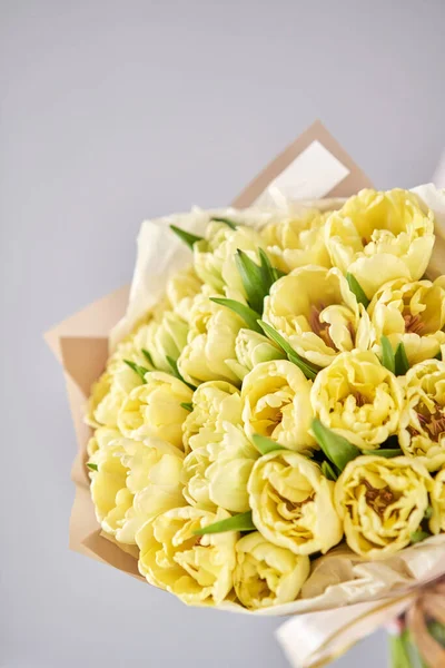 Amarelo tulipas cor pastel na mão da mulher. Jovem mulher bonita segurando um buquê de primavera. Bando de flores frescas de primavera cortadas em mãos femininas — Fotografia de Stock