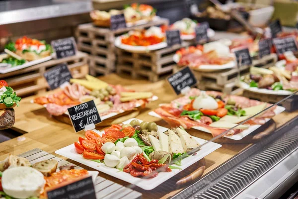 Különböző rágcsálnivalók és antipasti a vitrinben. Utcai élelmiszerpiac Firenzében, Olaszországban. — Stock Fotó