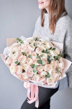 Kadınların elinde İranlı düğün çiçeği. Yeşil okaliptüslü soluk pembe ranunculus çiçekleri. Çiçekçi dükkanındaki çiçekçinin işi.