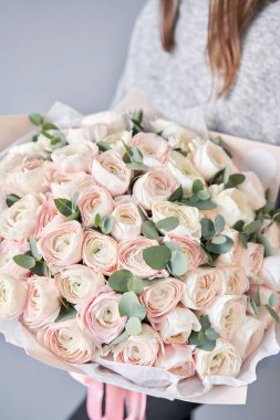 Kadınların elinde İranlı düğün çiçeği. Yeşil okaliptüslü soluk pembe ranunculus çiçekleri. Çiçekçi dükkanındaki çiçekçinin işi.