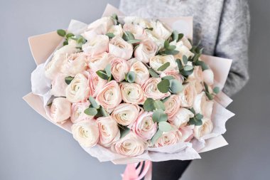 Kadınların elinde İranlı düğün çiçeği. Yeşil okaliptüslü soluk pembe ranunculus çiçekleri. Çiçekçi dükkanındaki çiçekçinin işi.