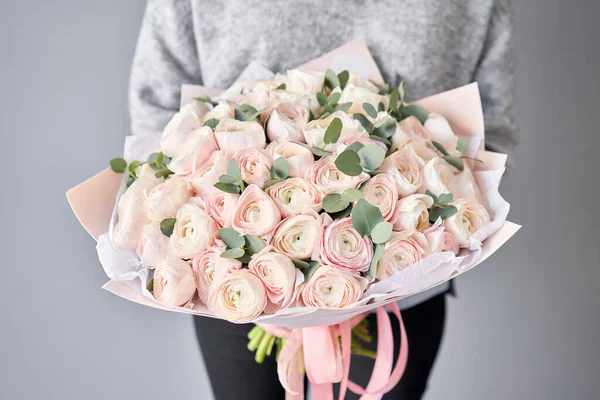 Buttercup persană în mâinile femeilor. Buchet de flori roz pal ranunculus cu eucalipt verde. Lucrarea florarului la un magazin de flori — Fotografie, imagine de stoc