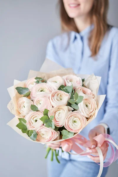 Buttercup persa em mãos de mulheres. Bunch rosa pálido ranúnculo flores com eucalipto verde. O trabalho da florista em uma loja de flores — Fotografia de Stock