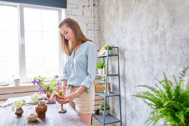 Genç bir çiçekçi kadın Kenzan 'da İkebana' da çiçek aranjmanı yapıyor. Makas ve budama makinesi kullanıyor. Mevsimlik yaz bahçesi çiçekleri.