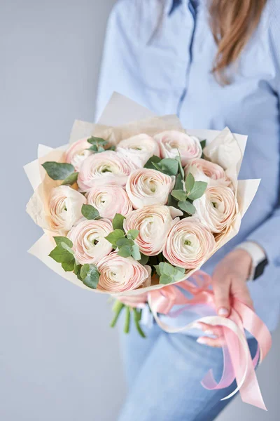 Ranuncolo persiano nelle mani delle donne. Mazzo di fiori ranuncoli rosa pallido con eucalipto verde. Il lavoro del fioraio in un negozio di fiori — Foto Stock