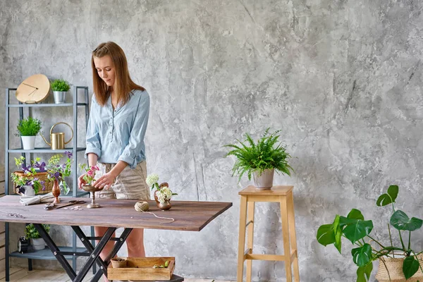 En ung kvinna florist skapa blomsterarrangemang Ikebana i kenzan. Använder sax och beskärare. Säsong sommar trädgård blommor. — Stockfoto