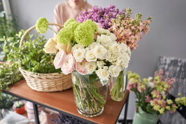 Concepto de tienda floral. Mujer florista crea arreglo floral en una canasta de mimbre. Hermoso ramo de flores mixtas. Hermoso grupo fresco. Entrega de flores . — Foto de Stock