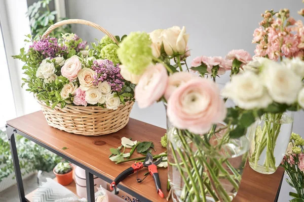 Educación en la escuela de floristería. Clase magistral en hacer ramos. Ramo de verano en una canasta de mimbre.. Aprendiendo arreglos florales, haciendo hermosos ramos con sus propias manos. Entrega de flores — Foto de Stock