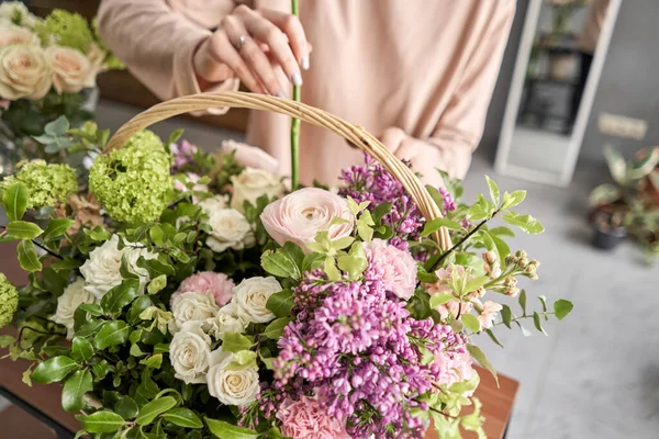 Floral shop concept . Florist woman creates flower arrangement in a wicker basket. Beautiful bouquet of mixed flowers. Handsome fresh bunch. Flowers delivery. — Stock Photo, Image