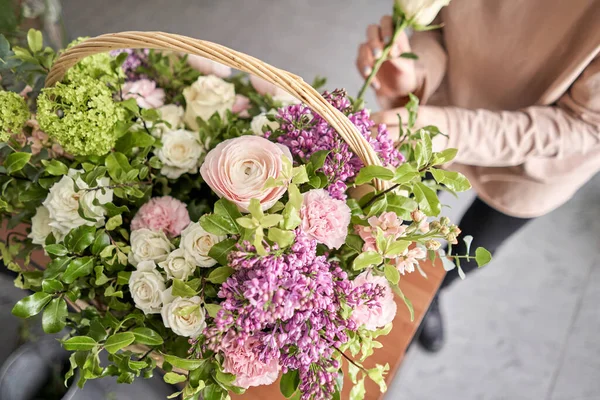 Concepto de tienda floral. Mujer florista crea arreglo floral en una canasta de mimbre. Hermoso ramo de flores mixtas. Hermoso grupo fresco. Entrega de flores . — Foto de Stock