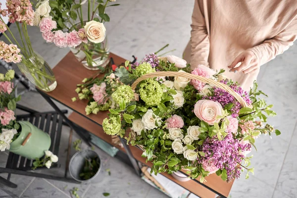 Floral shop concept . Florist woman creates flower arrangement in a wicker basket. Beautiful bouquet of mixed flowers. Handsome fresh bunch. Flowers delivery. — Stock Photo, Image