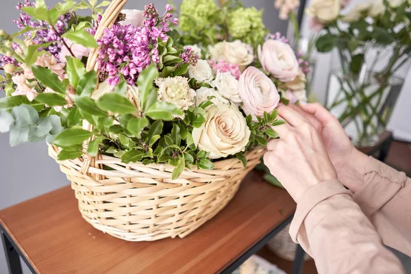 Bloemenwinkel concept. Bloemist vrouw creëert bloemstuk in een rieten mand. Mooi boeket van gemengde bloemen. Knap vers stel. Bloemen levering. — Stockfoto