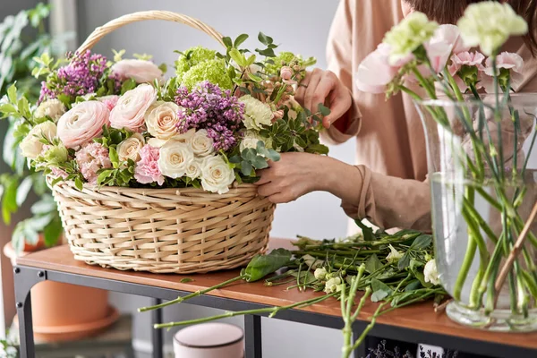 Concepto de tienda floral. Mujer florista crea arreglo floral en una canasta de mimbre. Hermoso ramo de flores mixtas. Hermoso grupo fresco. Entrega de flores . —  Fotos de Stock