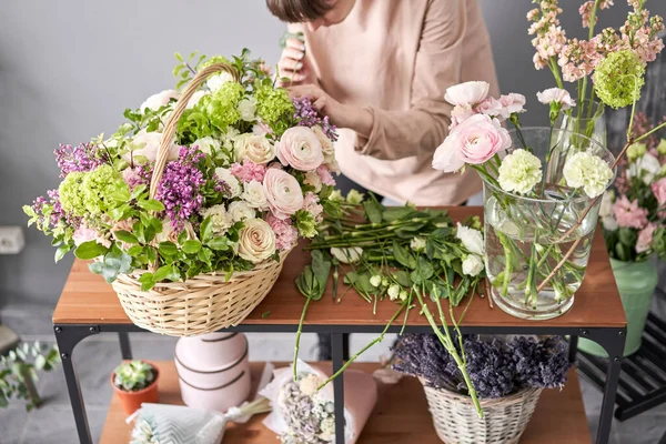 Concepto de tienda floral. Mujer florista crea arreglo floral en una canasta de mimbre. Hermoso ramo de flores mixtas. Hermoso grupo fresco. Entrega de flores . —  Fotos de Stock