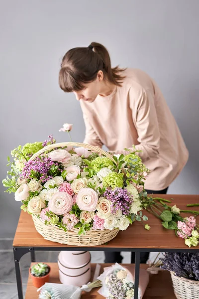 Concepto de tienda floral. Mujer florista crea arreglo floral en una canasta de mimbre. Hermoso ramo de flores mixtas. Hermoso grupo fresco. Entrega de flores . — Foto de Stock