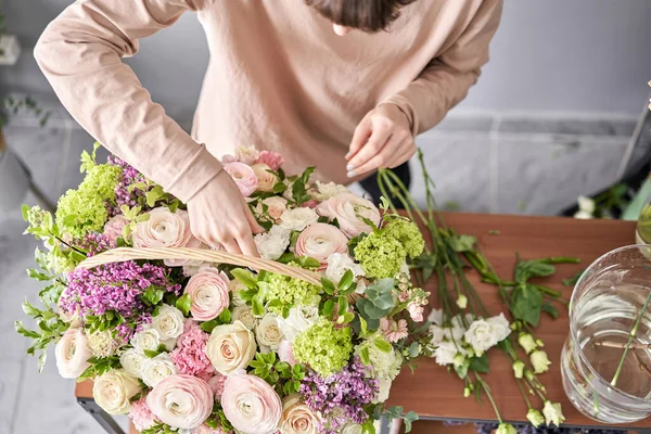 Conceito de loja floral. Mulher florista cria arranjo de flores em uma cesta de vime. Belo buquê de flores mistas. Bonito grupo fresco. Entrega de flores . — Fotografia de Stock