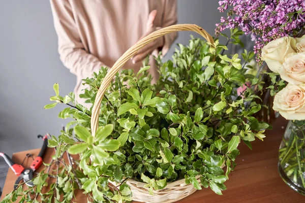 Concepto de tienda floral. Mujer florista crea arreglo floral en una canasta de mimbre. Hermoso ramo de flores mixtas. Hermoso grupo fresco. Entrega de flores . — Foto de Stock