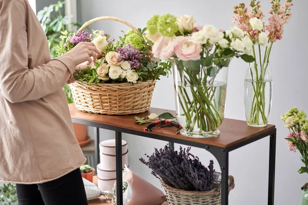 Concepto de tienda floral. Mujer florista crea arreglo floral en una canasta de mimbre. Hermoso ramo de flores mixtas. Hermoso grupo fresco. Entrega de flores . — Foto de Stock