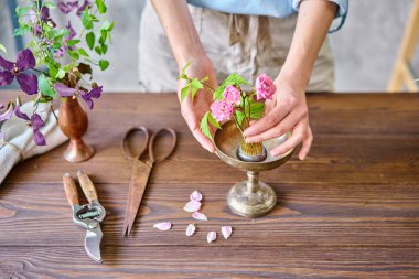 Genç bir çiçekçi kadın Kenzan 'da İkebana' da çiçek aranjmanı yapıyor. Makas ve budama makinesi kullanıyor. Mevsimlik yaz bahçesi çiçekleri.