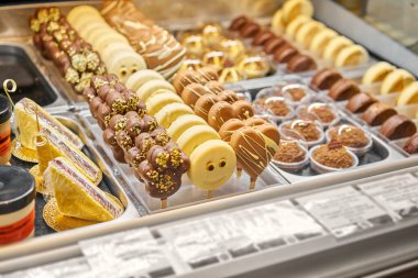 Bir pastanenin vitrininde sıra sıra çikolatalı pasta ve tatlı. İtalyan kafe veya lokantasında vitrin tatlıları.
