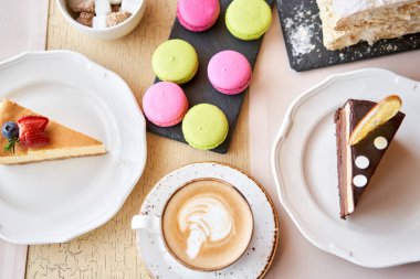 Breakfast in the cafe, morning coffee. Cappuccino and lots of desserts on the table. Napoleon, chocolate cake, cheesecake and macaroons.