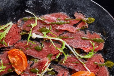 Biftek carpaccio soslu ve domatesli siyah masa. Restoran menüsü, doğal ve organik gıda konsepti..