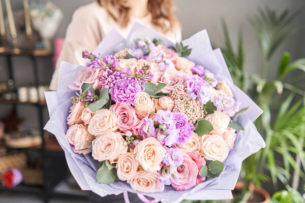 European floral shop. Beautiful bouquet of mixed flowers in womans hands. the work of the florist at a flower shop. Delivery fresh cut flower.