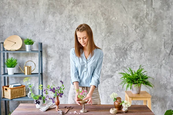 En ung kvinna florist skapa blomsterarrangemang Ikebana i kenzan. Använder sax och beskärare. Säsong sommar trädgård blommor. — Stockfoto