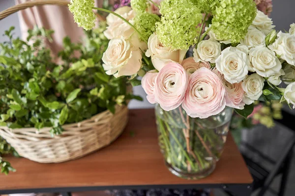 Concepto de tienda floral. Mujer florista crea arreglo floral en una canasta de mimbre. Hermoso ramo de flores mixtas. Hermoso grupo fresco. Entrega de flores . — Foto de Stock