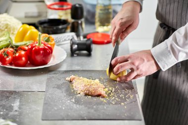 Şef tavuk doğrayıp terbiye ediyor. Restoran mutfağında profesyonel bir aşçı..